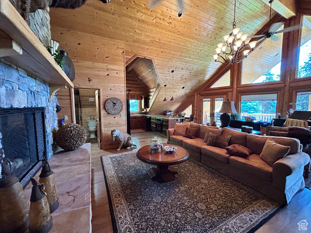 Living room with a stone fireplace, wooden ceiling, hardwood / wood-style flooring, and wood walls