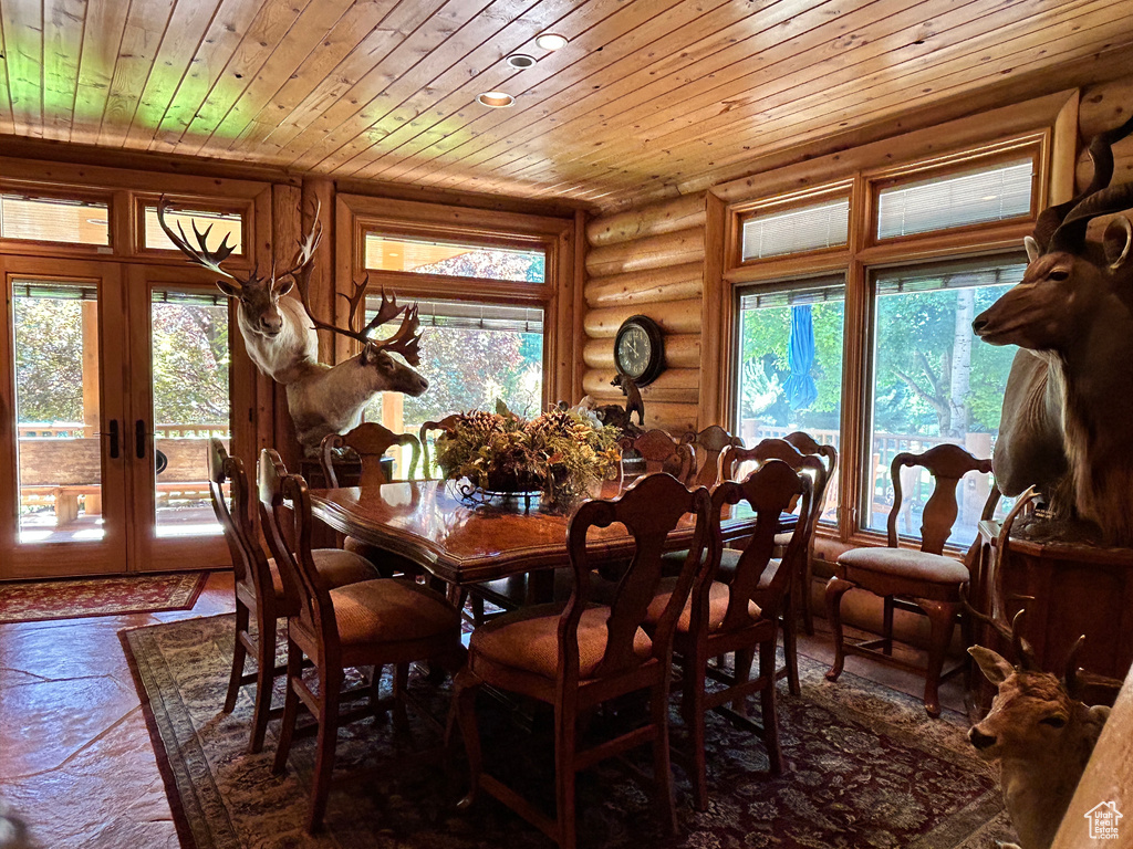 Dining room with a healthy amount of sunlight, log walls, and wood ceiling