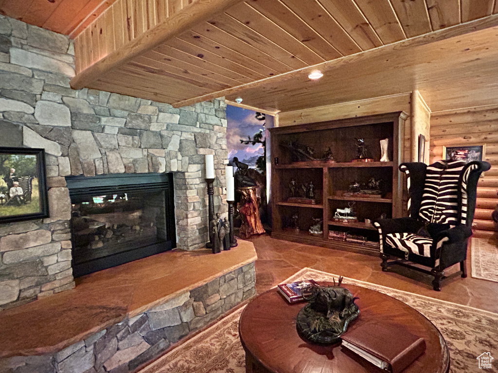 Living room featuring a stone fireplace, wooden ceiling, tile flooring, and log walls
