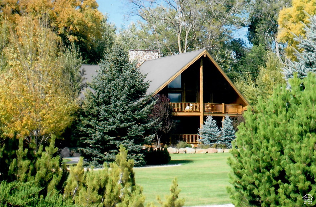 Back of house with a yard and a balcony