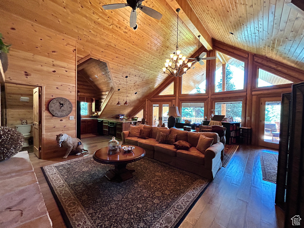 Living room with wooden ceiling, wooden walls, wood-type flooring, and ceiling fan with notable chandelier