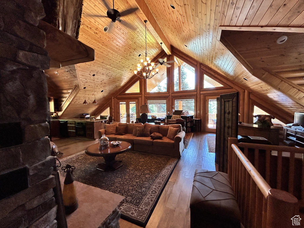 Living room with ceiling fan with notable chandelier, vaulted ceiling with beams, hardwood / wood-style floors, and wood ceiling