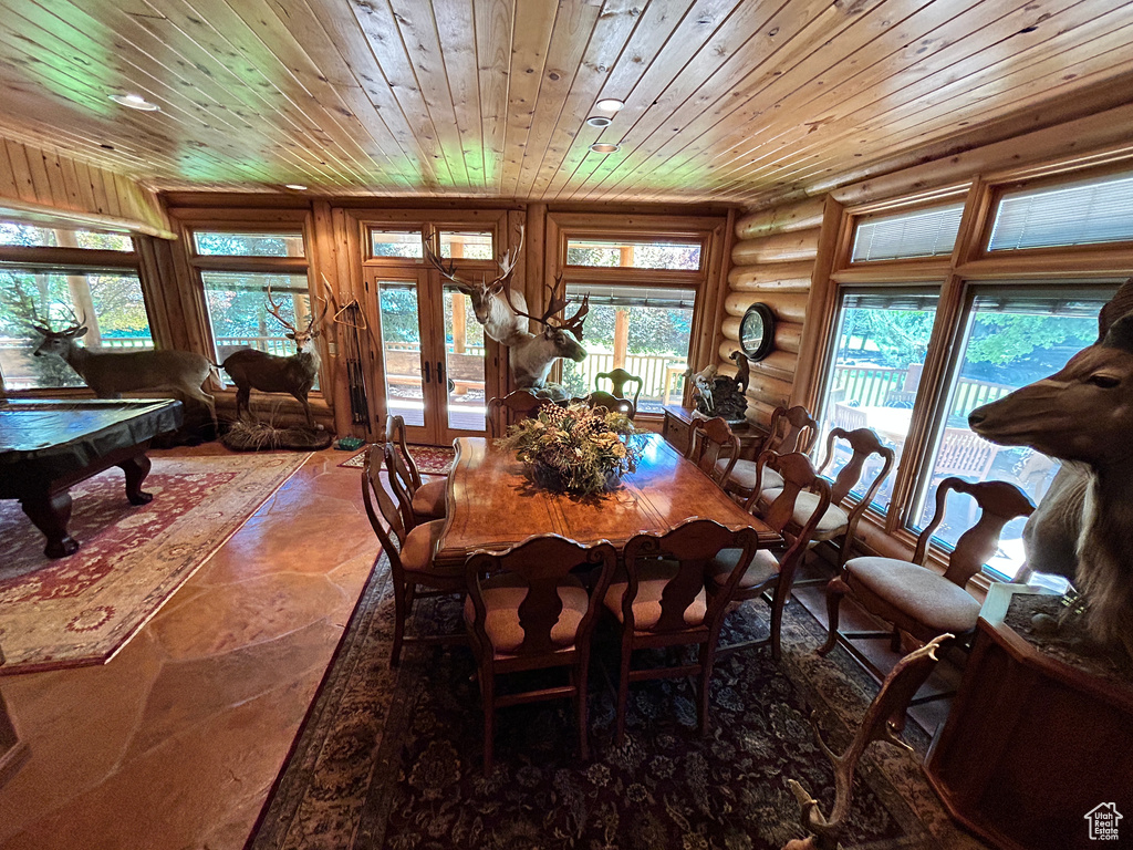 Dining space featuring a wealth of natural light, wood ceiling, log walls, and french doors