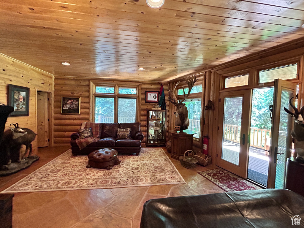 Living room with a wealth of natural light, log walls, french doors, and wood ceiling