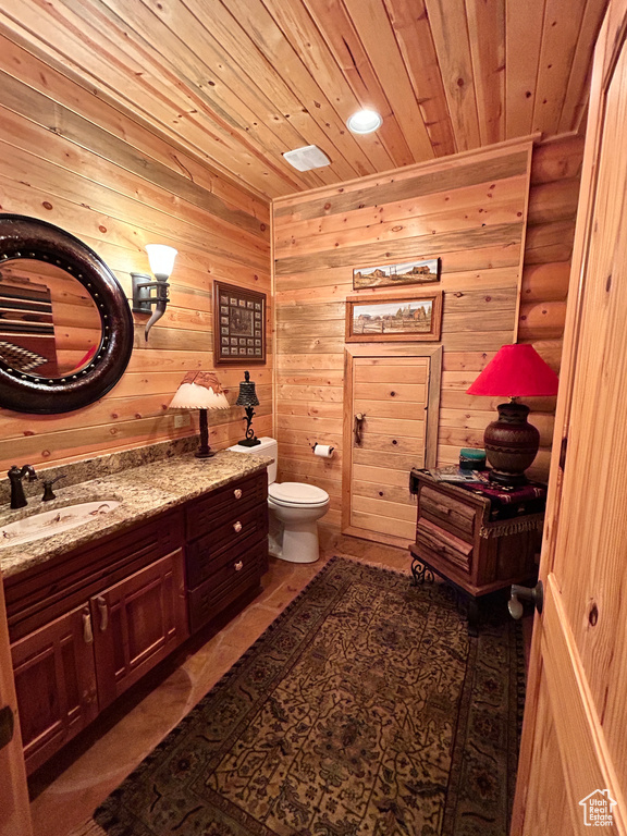 Bathroom with wood walls, vanity, toilet, and wood ceiling