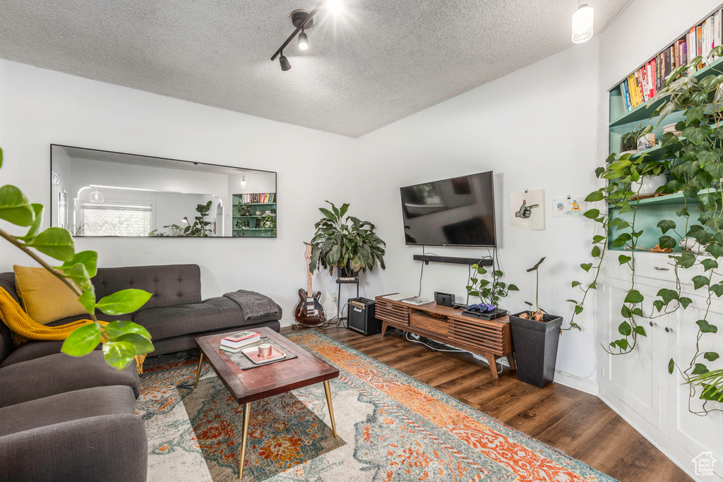 Living room with a textured ceiling, dark hardwood / wood-style floors, and track lighting