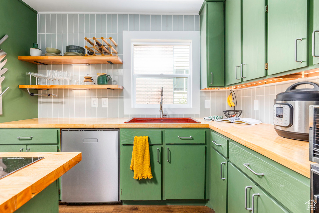 Kitchen with butcher block counters, sink, backsplash, and green cabinetry