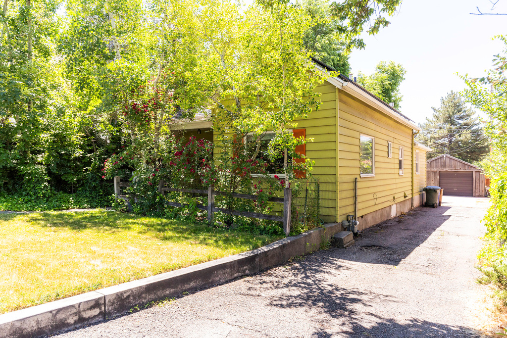 View of property exterior featuring a garage and a lawn