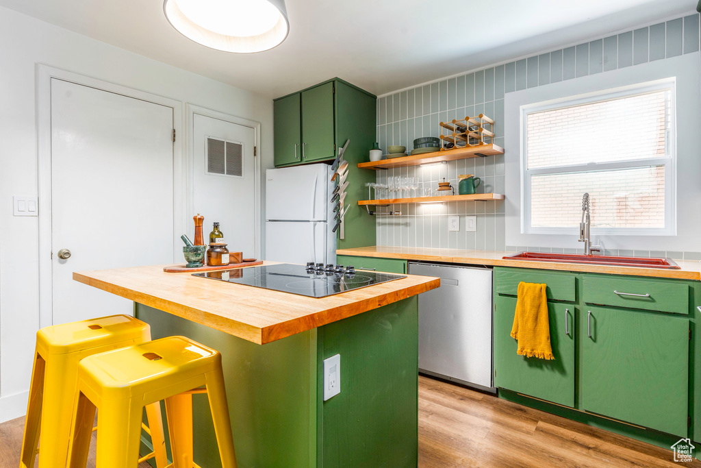 Kitchen featuring white refrigerator, light hardwood / wood-style flooring, backsplash, butcher block countertops, and stainless steel dishwasher