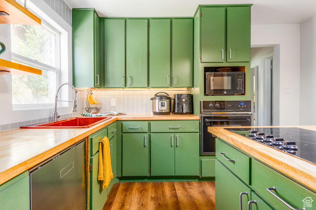 Kitchen with black appliances, a wealth of natural light, tasteful backsplash, and green cabinetry