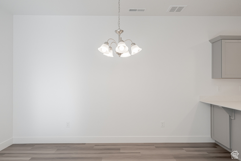 Unfurnished dining area with light hardwood / wood-style flooring and a chandelier