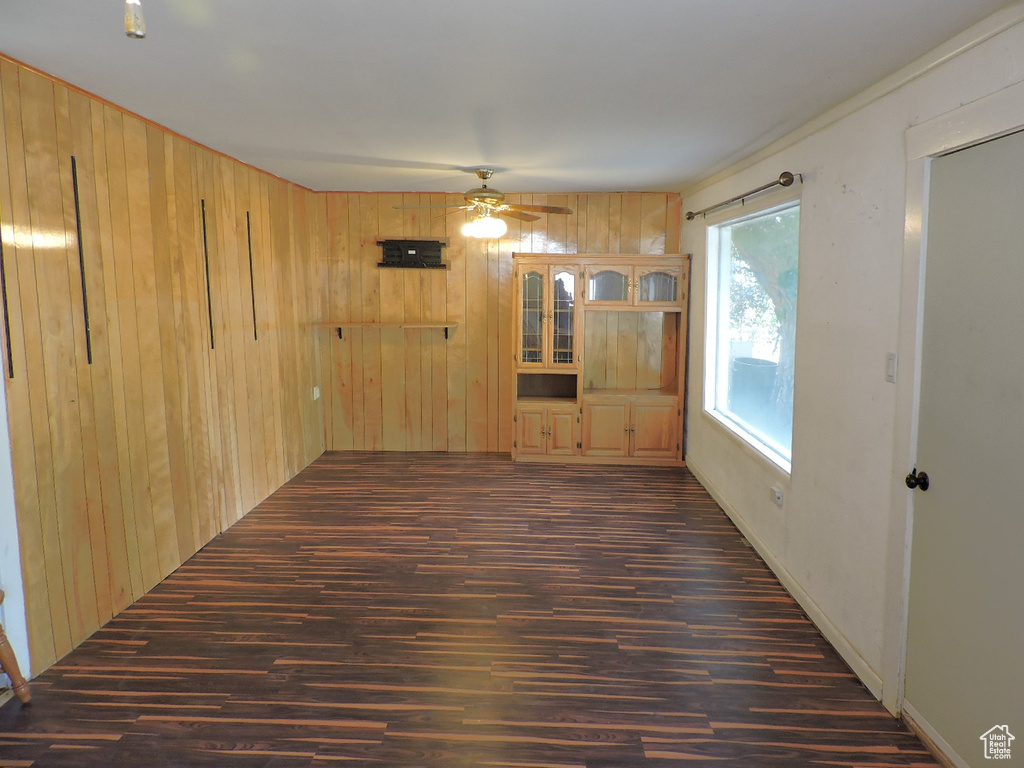 Spare room featuring ceiling fan, wood walls, and hardwood / wood-style floors