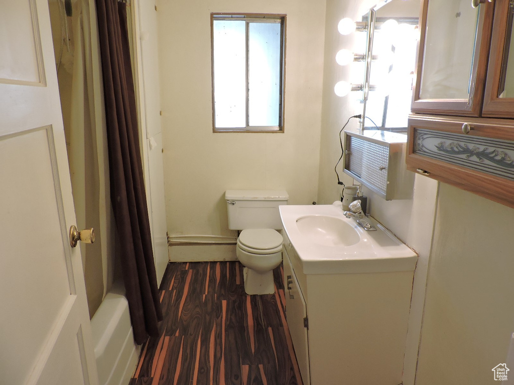 Full bathroom with shower / bathtub combination with curtain, hardwood / wood-style flooring, toilet, and vanity