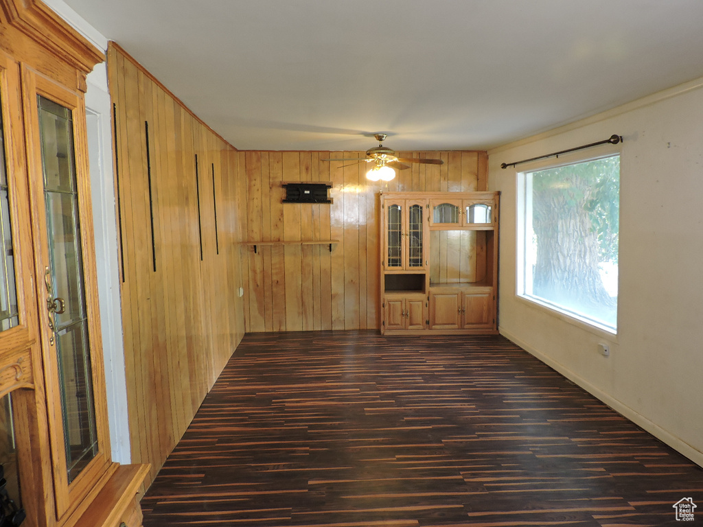 Unfurnished living room featuring wooden walls, ceiling fan, and hardwood / wood-style floors