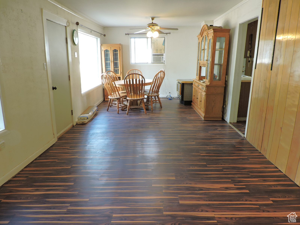 Dining area featuring dark wood-type flooring, ornamental molding, and ceiling fan