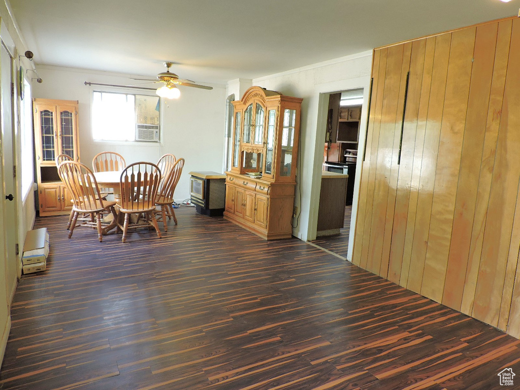 Dining space with dark hardwood / wood-style floors, wooden walls, and ceiling fan