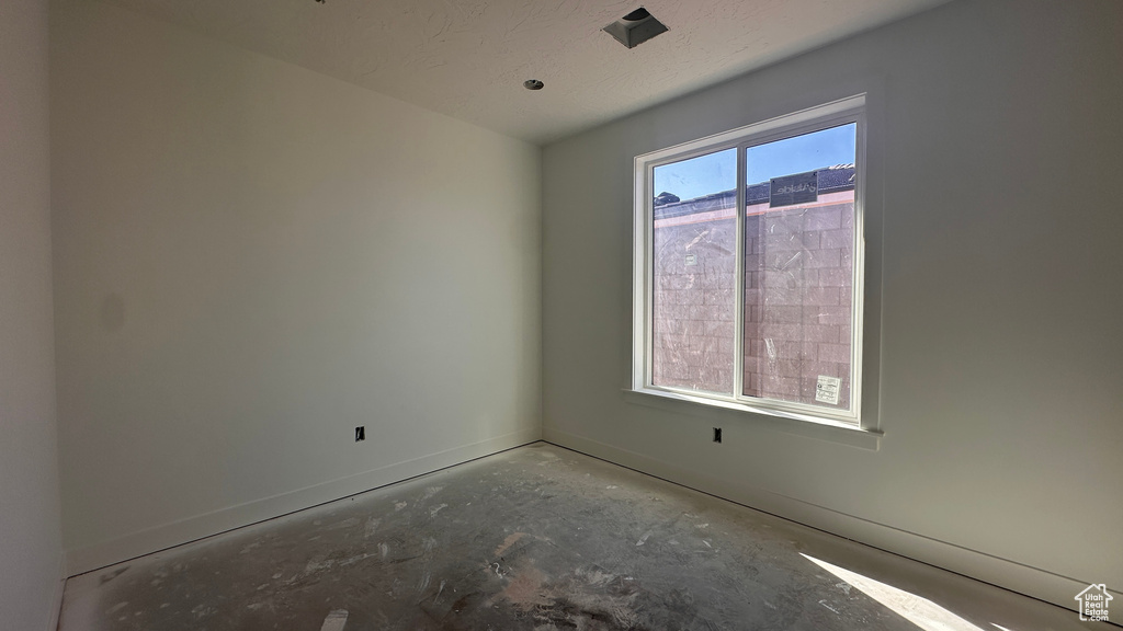 Empty room featuring a textured ceiling, concrete floors, and plenty of natural light