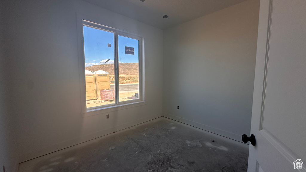 Spare room with a wealth of natural light, concrete flooring, and a mountain view