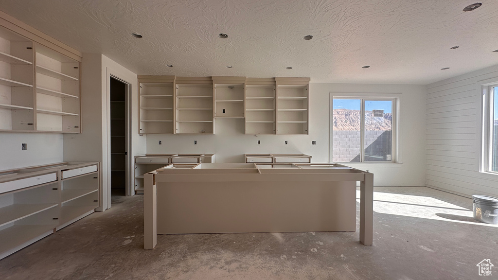 Kitchen featuring concrete floors, a mountain view, a center island, and a textured ceiling