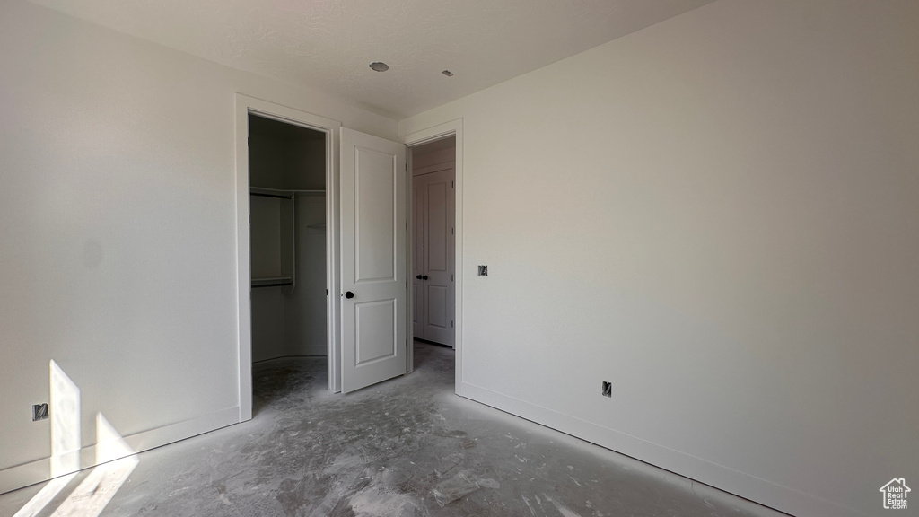 Unfurnished bedroom with a closet, a walk in closet, and concrete flooring