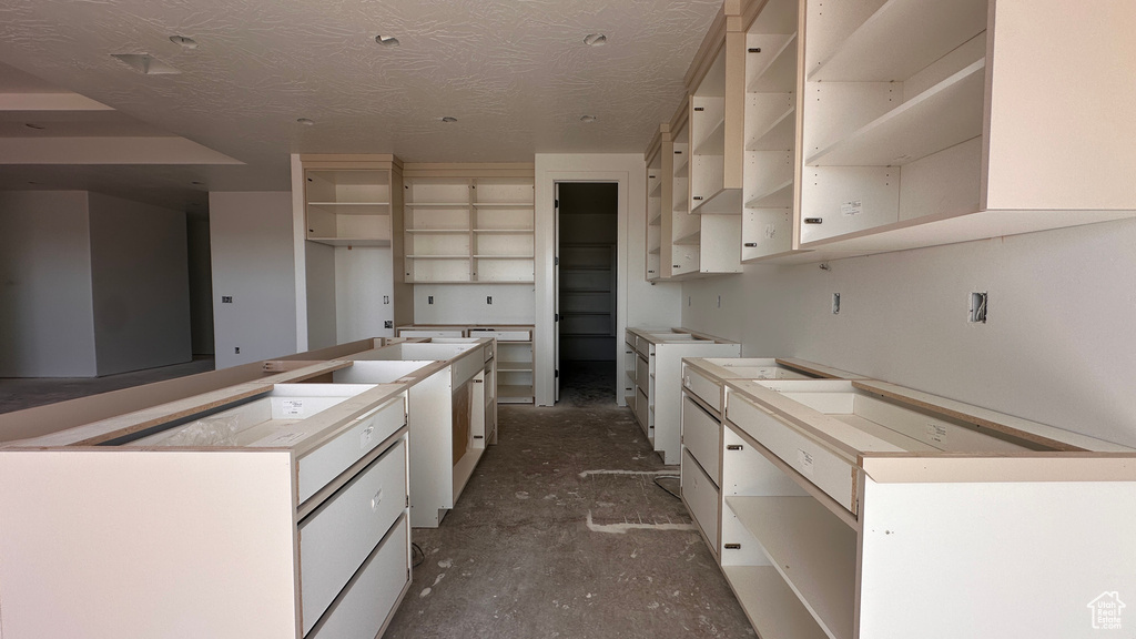 Kitchen featuring a center island, concrete flooring, and a textured ceiling