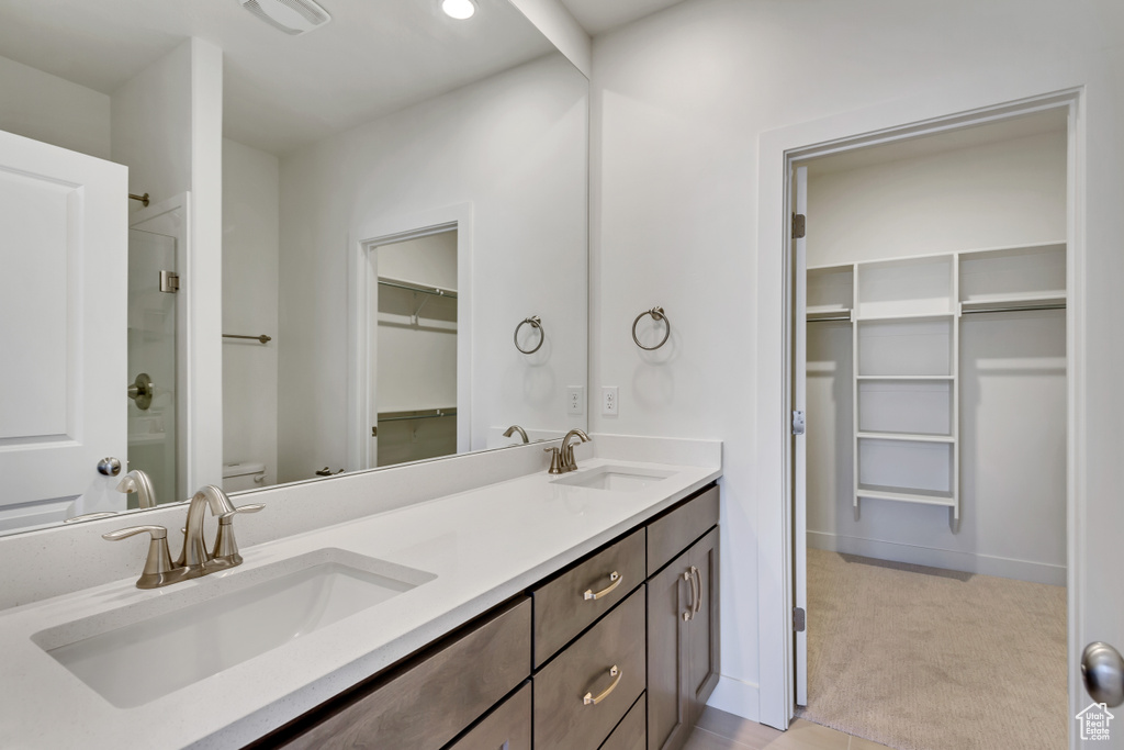 Bathroom with a shower with shower door, dual vanity, and toilet