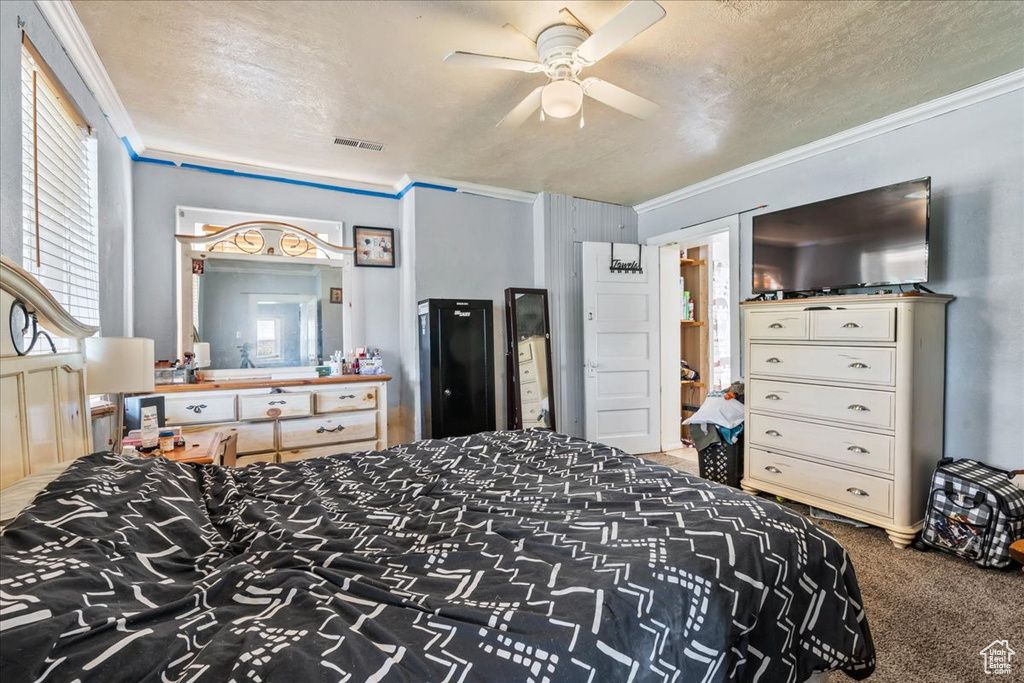 Bedroom featuring ceiling fan, carpet floors, a textured ceiling, and ornamental molding