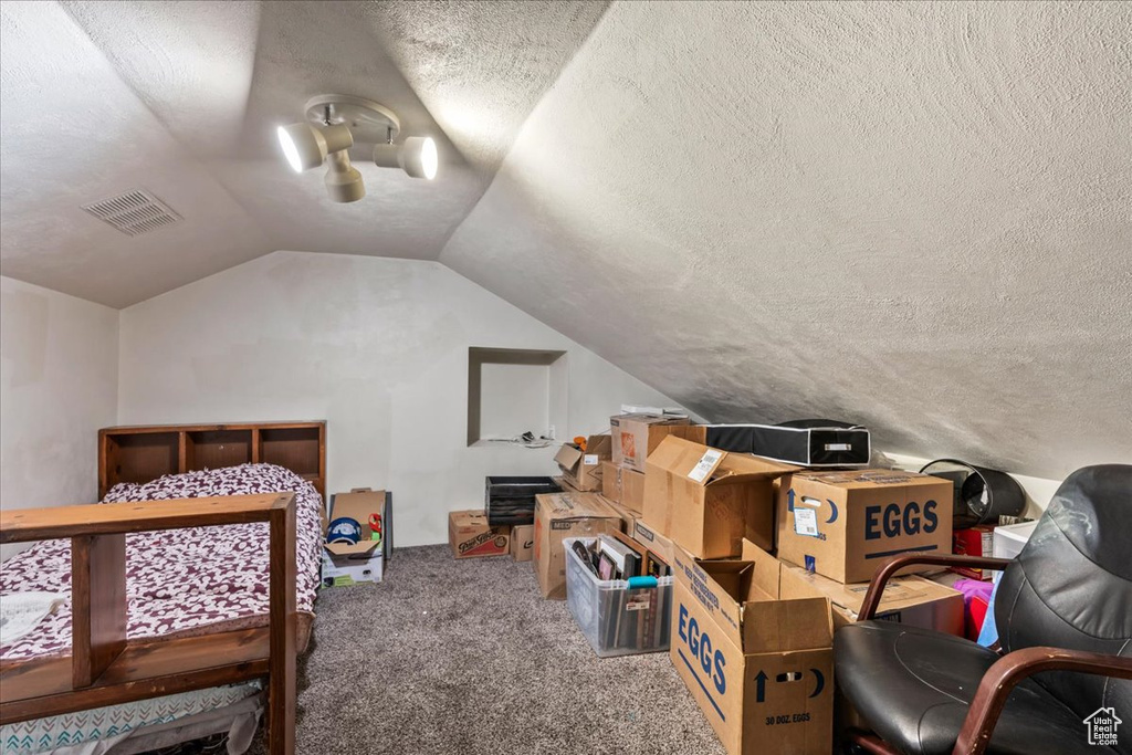 Bedroom with a textured ceiling, lofted ceiling, and carpet floors