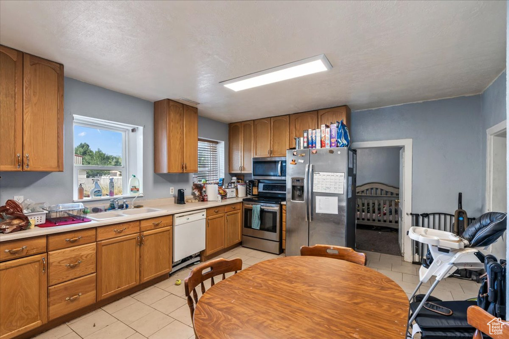 Kitchen with appliances with stainless steel finishes, sink, and light tile floors