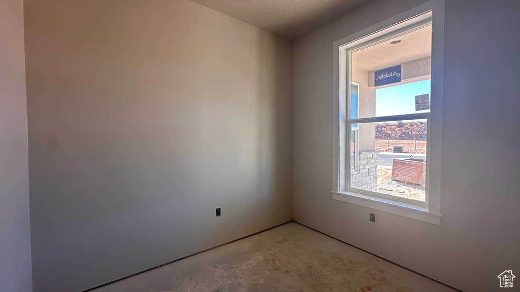 Unfurnished room with a textured ceiling and concrete flooring