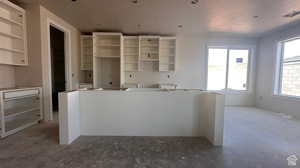 Kitchen with a textured ceiling, a kitchen island, and a wealth of natural light