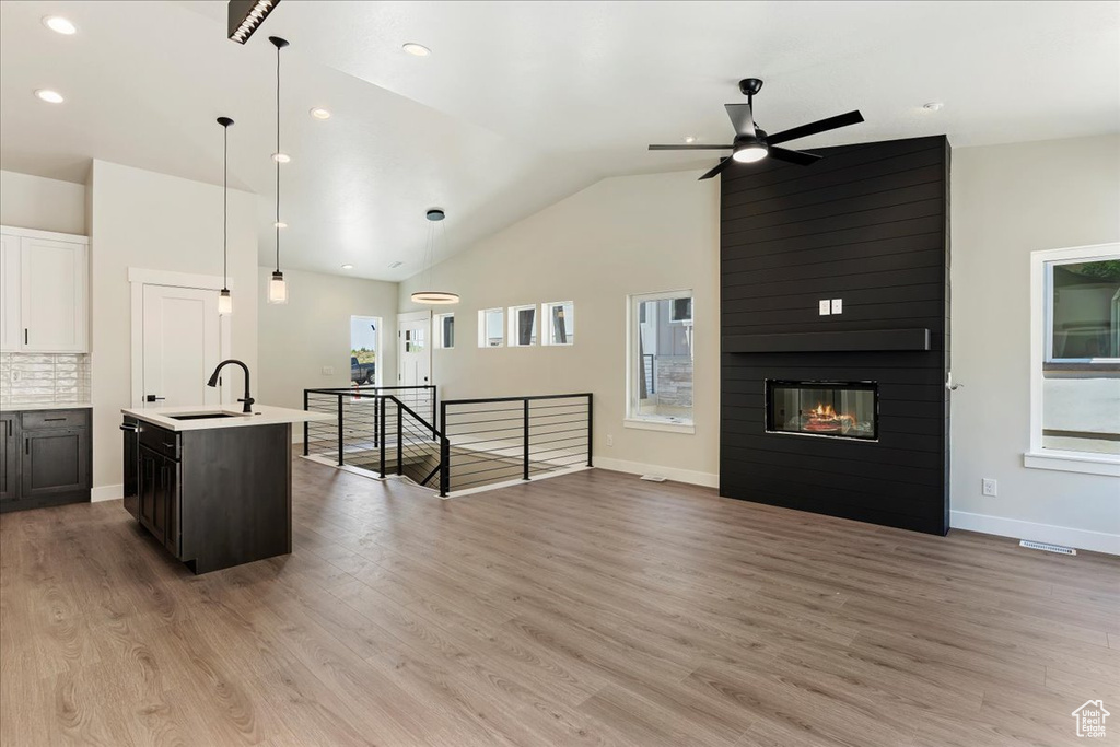 Kitchen featuring hanging light fixtures, plenty of natural light, a center island with sink, and light hardwood / wood-style floors