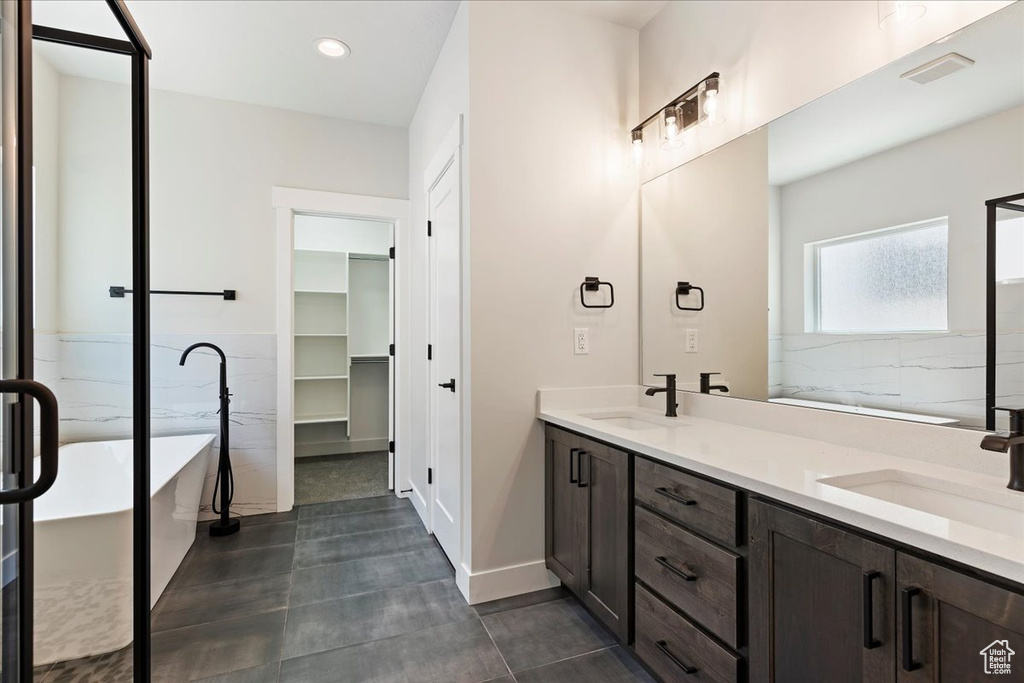 Bathroom featuring a tub, tile flooring, large vanity, and double sink