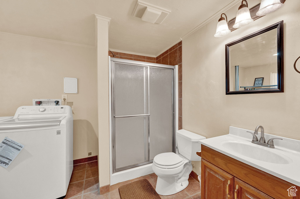 Bathroom featuring washer / dryer, oversized vanity, toilet, tile flooring, and walk in shower