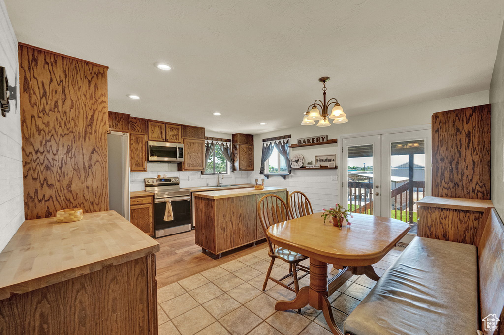 Kitchen with an inviting chandelier, appliances with stainless steel finishes, light hardwood / wood-style flooring, pendant lighting, and sink