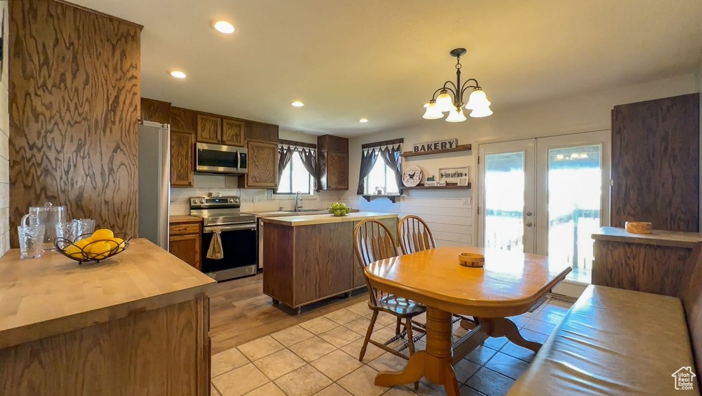 Kitchen with a wealth of natural light, appliances with stainless steel finishes, french doors, and pendant lighting