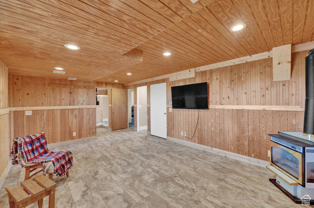 Living area featuring wooden walls, light tile floors, a wood stove, and wooden ceiling