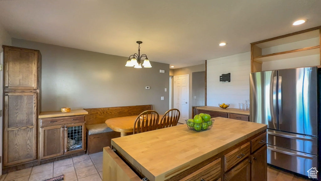 Kitchen with butcher block counters, stainless steel fridge, a kitchen island, pendant lighting, and light tile floors