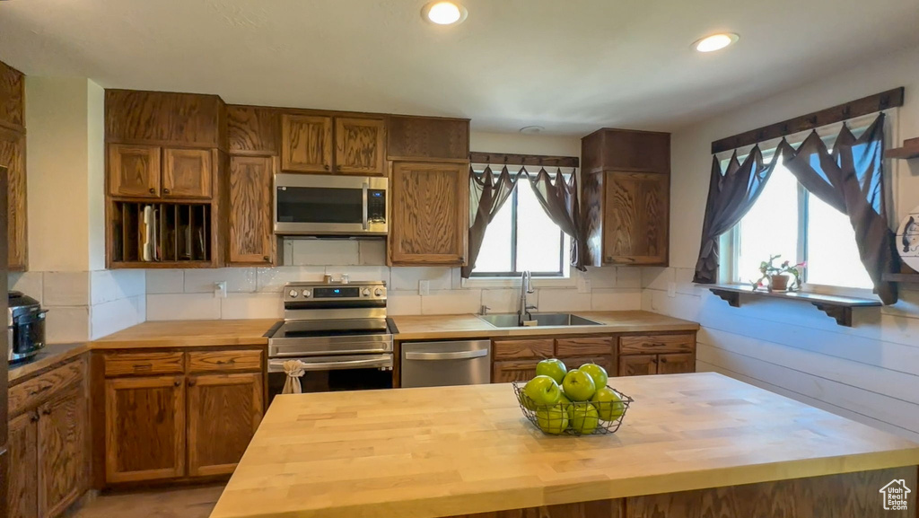 Kitchen featuring sink, stainless steel appliances, backsplash, and wooden counters