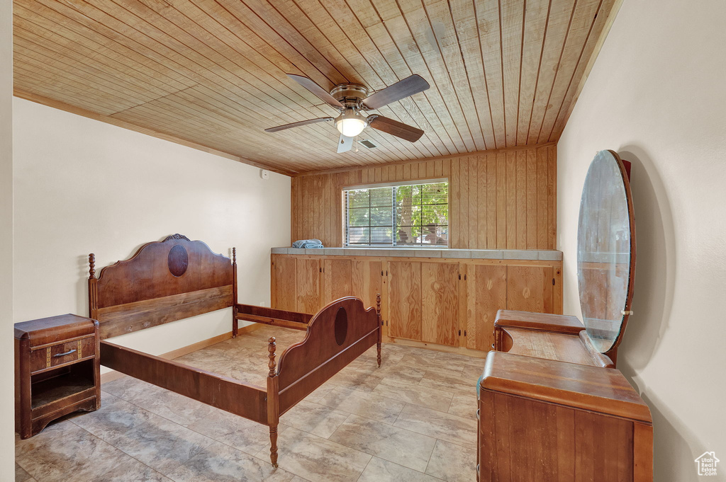 Bedroom with wooden ceiling, wooden walls, ceiling fan, and tile floors