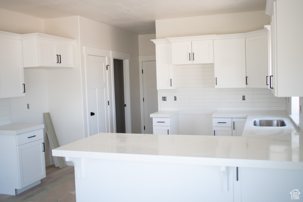 Kitchen with a peninsula, decorative backsplash, white cabinetry, and light wood-style flooring