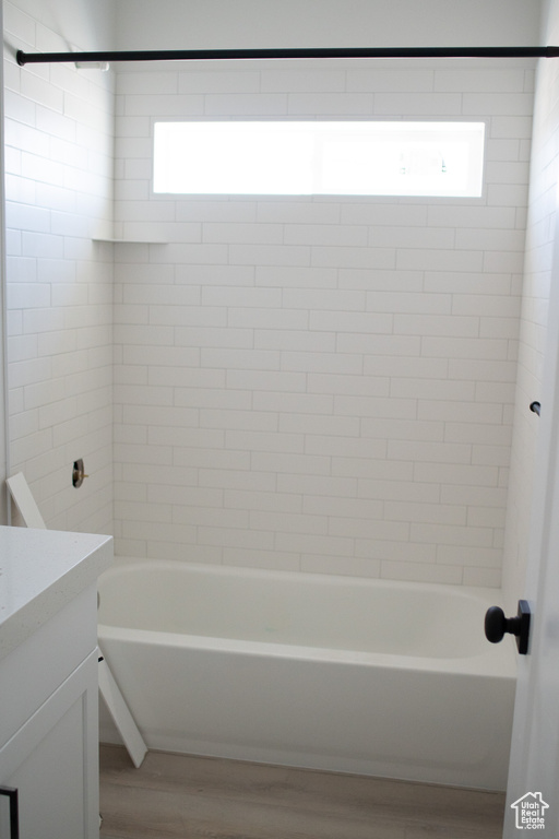 Full bath featuring wood finished floors, vanity, healthy amount of natural light, and shower / bathtub combination