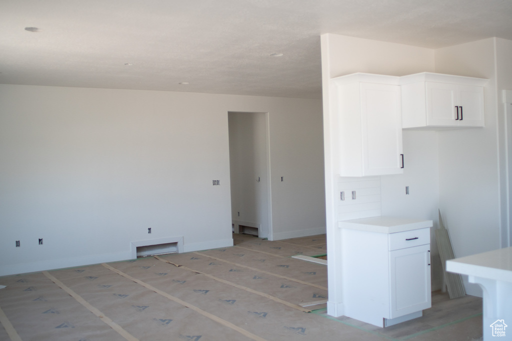 Kitchen with white cabinetry, light countertops, baseboards, and open floor plan