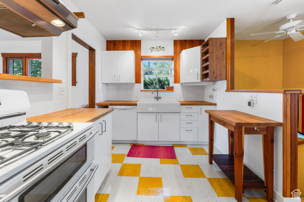 Kitchen with ceiling fan, white appliances, premium range hood, sink, and white cabinets