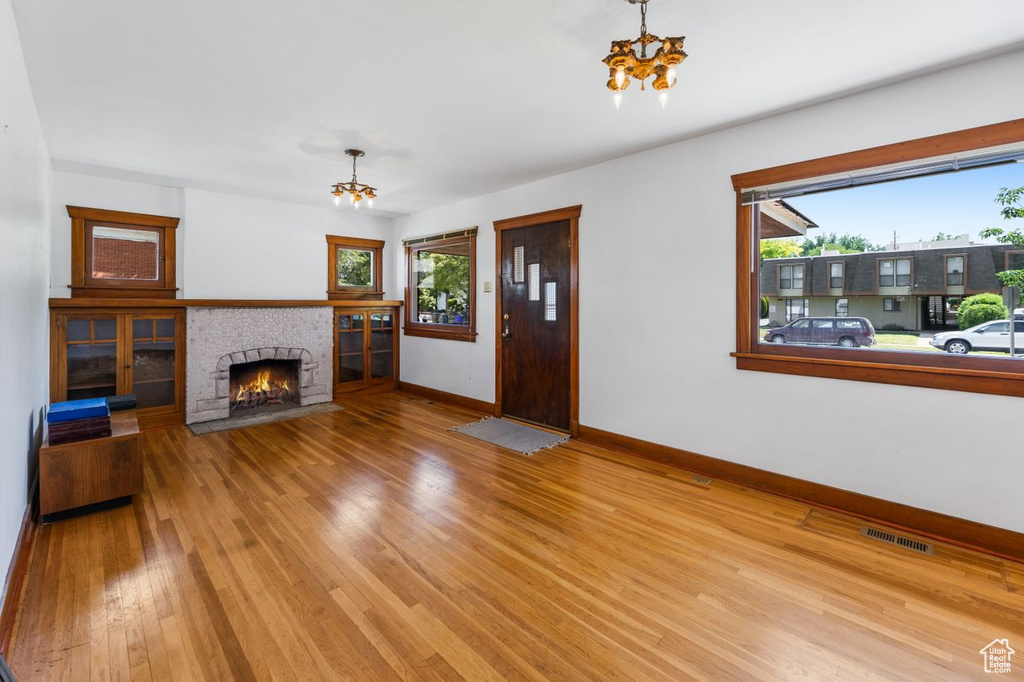 Living room with a wealth of natural light, an inviting chandelier, and light wood-type flooring