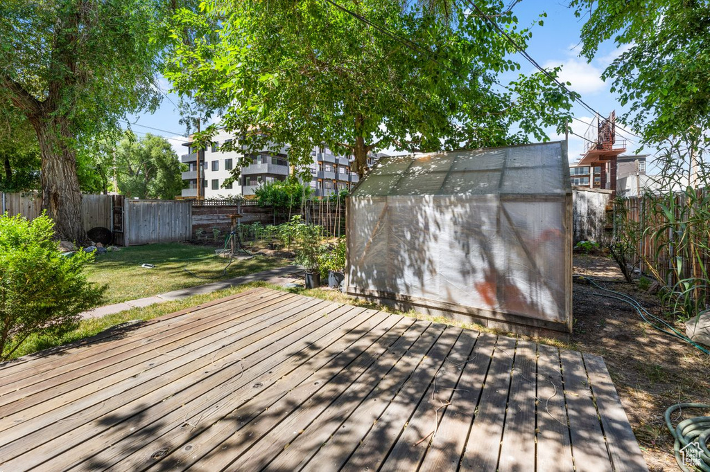 Wooden terrace featuring a lawn and a storage shed