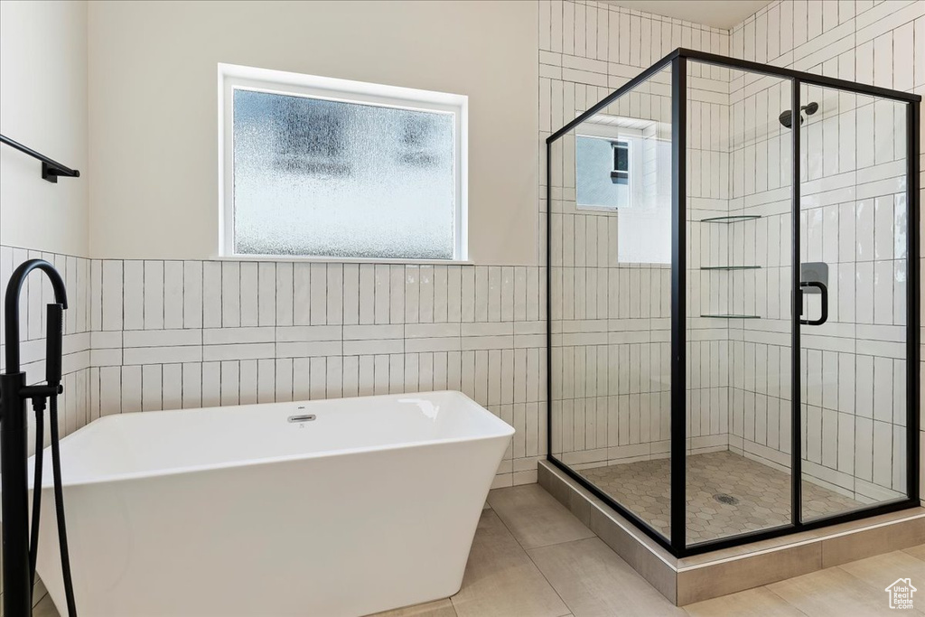 Bathroom with shower with separate bathtub, tile walls, and tile floors