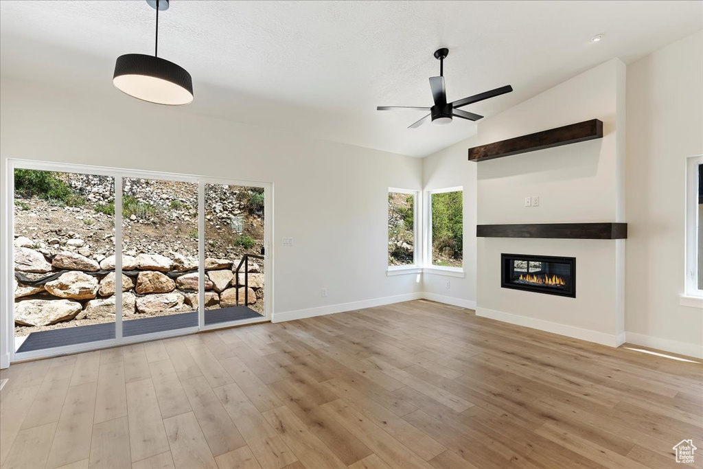 Unfurnished living room with light hardwood / wood-style floors, ceiling fan, and vaulted ceiling