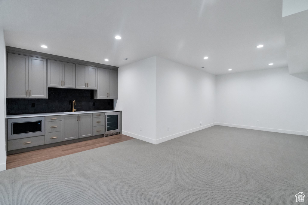 Kitchen with beverage cooler, sink, gray cabinets, and tasteful backsplash