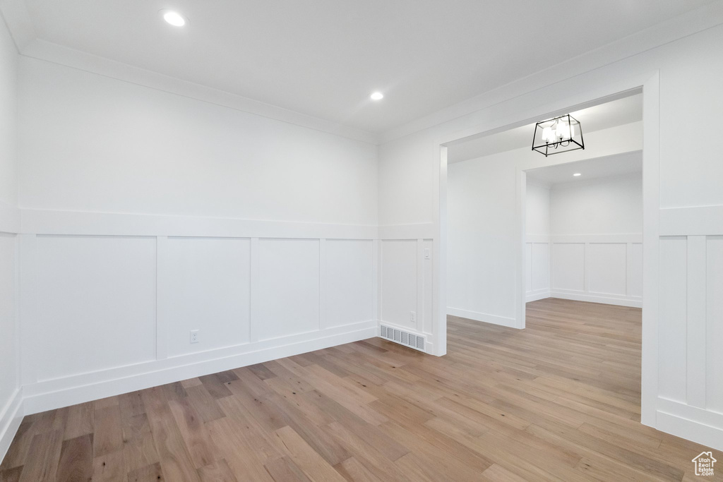 Spare room featuring a notable chandelier, ornamental molding, and light hardwood / wood-style floors